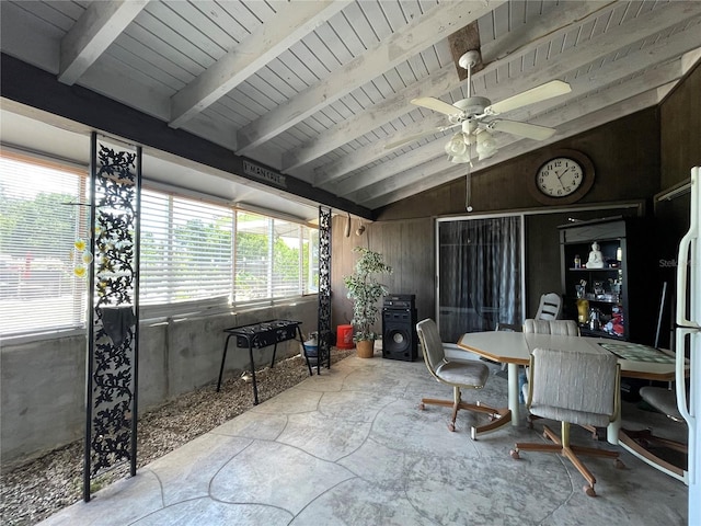 home office with wooden ceiling, vaulted ceiling with beams, wood walls, and ceiling fan