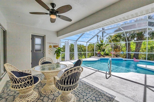 view of pool with ceiling fan, glass enclosure, and a patio area