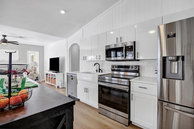 kitchen with sink, white cabinets, ceiling fan, light hardwood / wood-style flooring, and appliances with stainless steel finishes