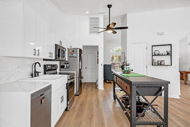 kitchen with appliances with stainless steel finishes, ceiling fan, light hardwood / wood-style flooring, and white cabinets