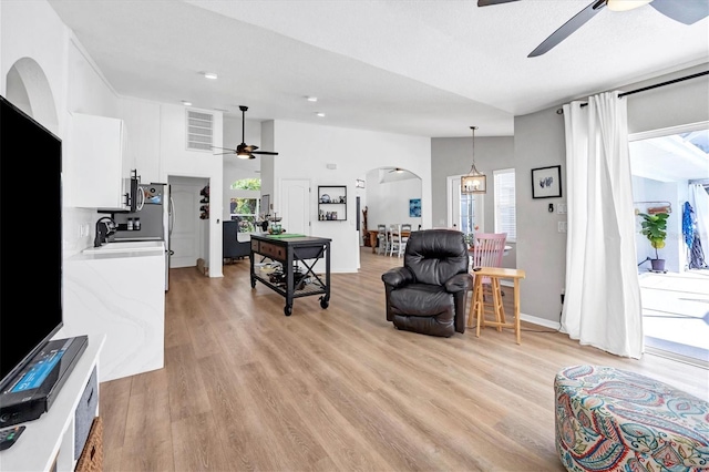 living room featuring a healthy amount of sunlight, light hardwood / wood-style flooring, a towering ceiling, and sink