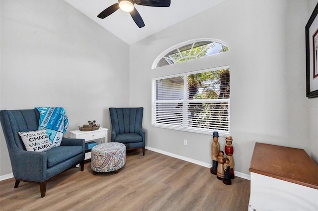 living area featuring hardwood / wood-style flooring, ceiling fan, and vaulted ceiling