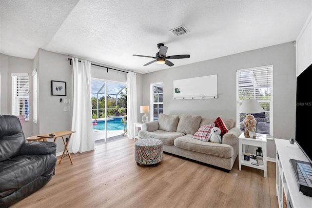 living room featuring ceiling fan, a healthy amount of sunlight, and light wood-type flooring