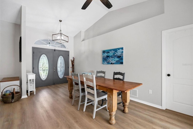 dining area featuring lofted ceiling, french doors, ceiling fan with notable chandelier, and light hardwood / wood-style flooring