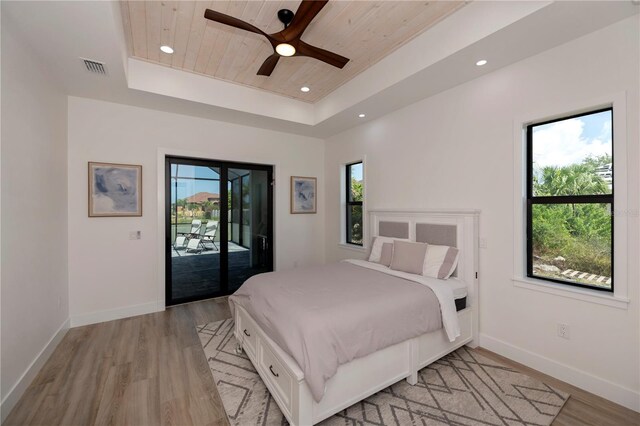 bedroom featuring light hardwood / wood-style flooring, access to outside, wooden ceiling, ceiling fan, and a raised ceiling