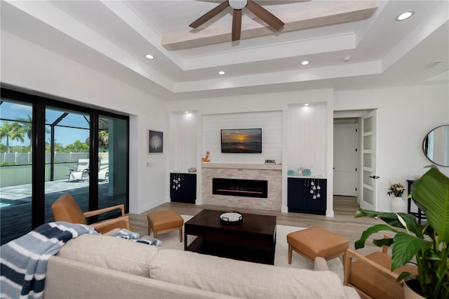 living room featuring ceiling fan, hardwood / wood-style flooring, and a tray ceiling