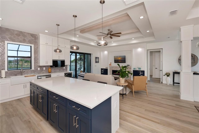 kitchen featuring light hardwood / wood-style floors, hanging light fixtures, ceiling fan, a tray ceiling, and white cabinetry