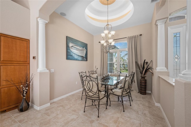 dining area featuring decorative columns, a raised ceiling, and an inviting chandelier