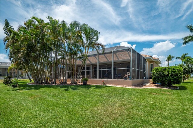 rear view of house with glass enclosure and a yard