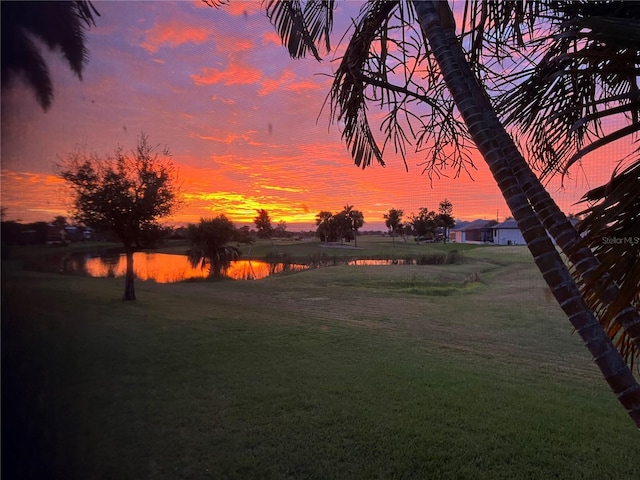 yard at dusk featuring a water view