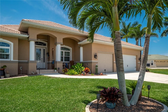 mediterranean / spanish house featuring concrete driveway, a tiled roof, an attached garage, a front lawn, and stucco siding