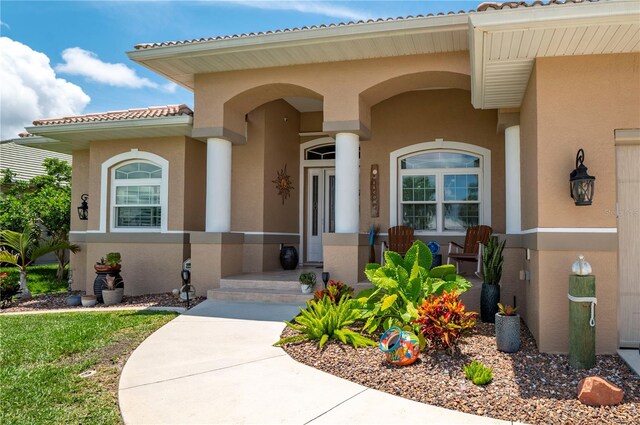 property entrance with covered porch, a tile roof, and stucco siding