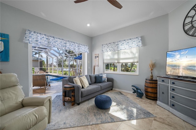 living area with a sunroom, light tile patterned flooring, ceiling fan, and baseboards