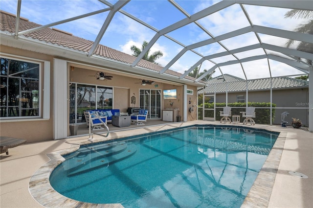 outdoor pool with ceiling fan, glass enclosure, outdoor lounge area, and a patio area