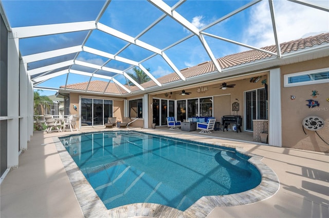 pool featuring glass enclosure, a patio area, and a ceiling fan