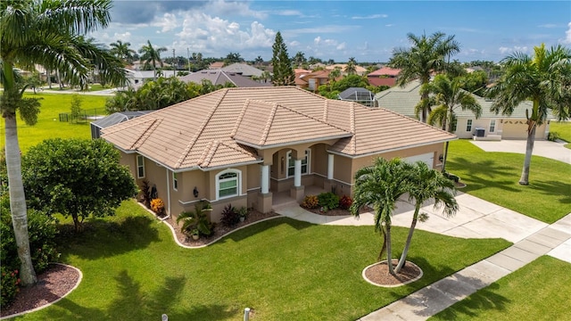 view of front of property featuring driveway, a tile roof, a front yard, and stucco siding