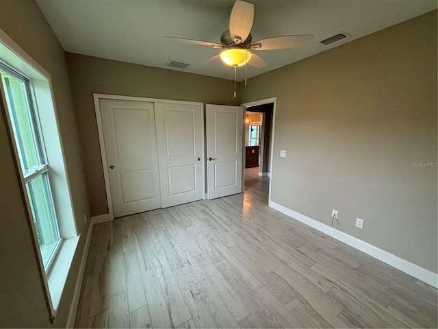 unfurnished bedroom featuring light wood-type flooring, ceiling fan, and a closet