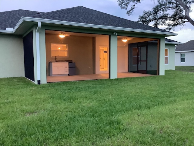 rear view of property with sink, a yard, and a patio