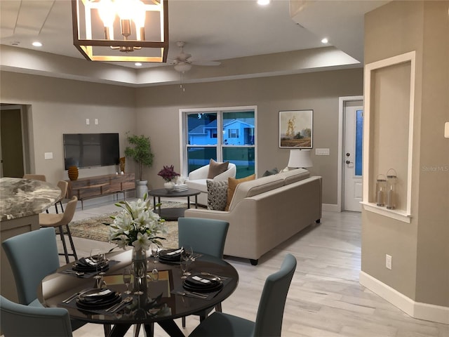 living room with ceiling fan with notable chandelier and light hardwood / wood-style flooring