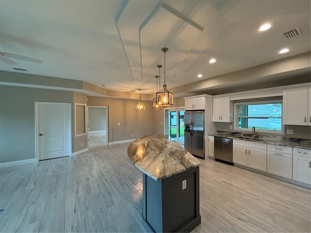 kitchen with hanging light fixtures, appliances with stainless steel finishes, white cabinets, and a kitchen island