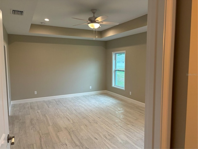 unfurnished room with a tray ceiling, light hardwood / wood-style flooring, and ceiling fan