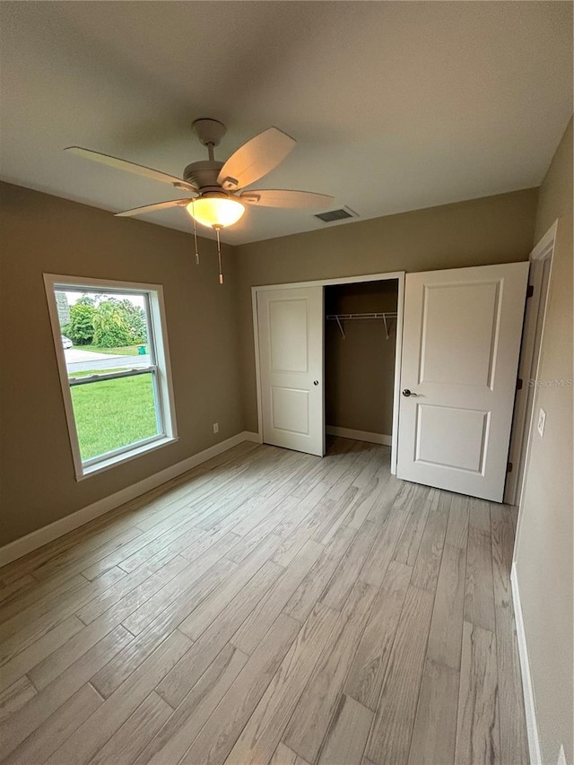 unfurnished bedroom featuring ceiling fan, a closet, and light wood-type flooring