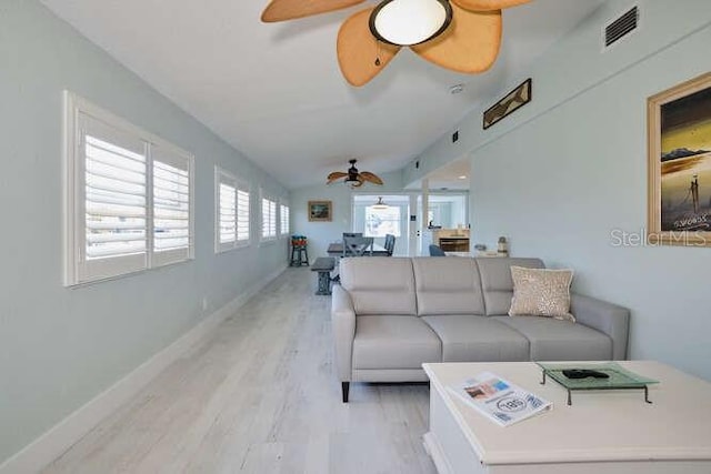 living room featuring a wealth of natural light, ceiling fan, lofted ceiling, and light wood-type flooring