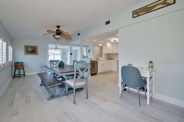 dining space with ceiling fan, light wood-type flooring, sink, and a wealth of natural light