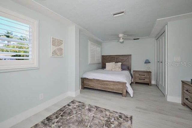 bedroom with ceiling fan, light wood-type flooring, and a closet