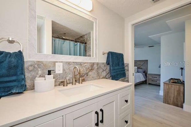 bathroom featuring vanity, a shower with shower curtain, a textured ceiling, tasteful backsplash, and wood-type flooring