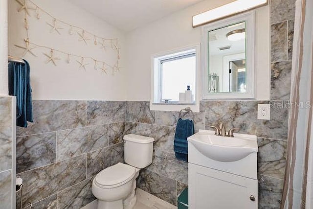 bathroom with vanity, toilet, and tile walls