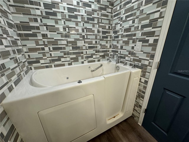 bathroom with tile walls, hardwood / wood-style floors, and a bathing tub