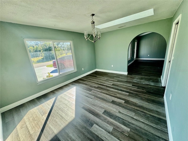 unfurnished dining area featuring an inviting chandelier, dark hardwood / wood-style floors, and a textured ceiling