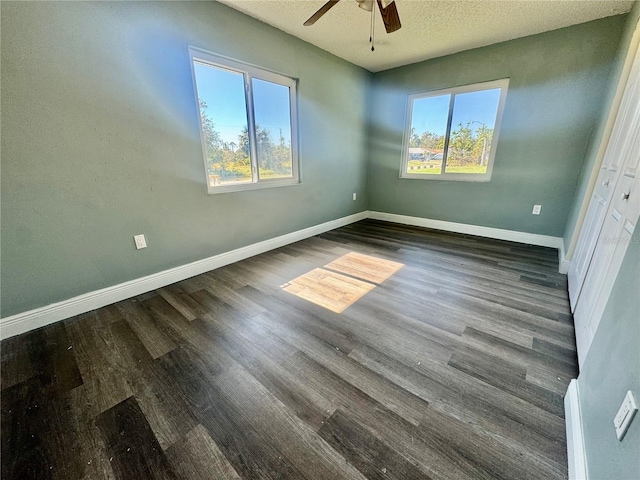 unfurnished bedroom featuring multiple windows, ceiling fan, dark hardwood / wood-style floors, and a textured ceiling