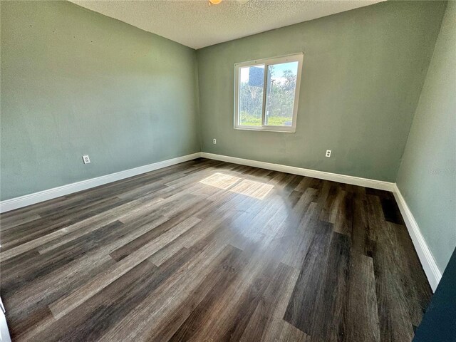 unfurnished room featuring dark hardwood / wood-style flooring and a textured ceiling