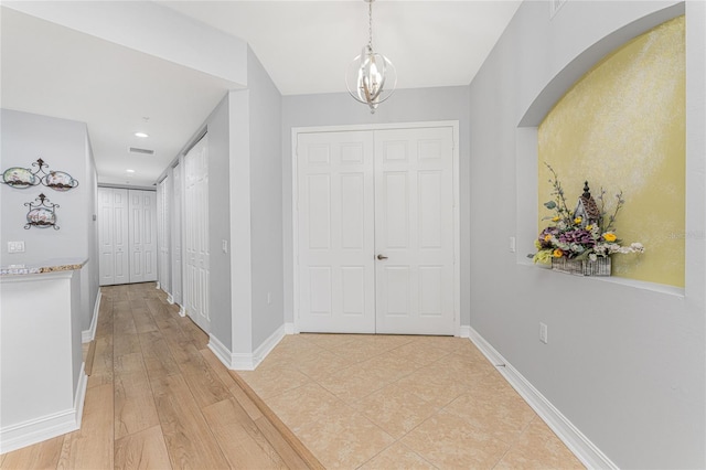 hallway with an inviting chandelier and light wood-type flooring