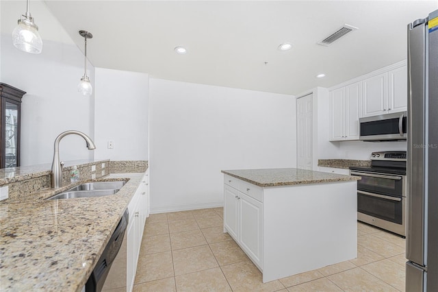 kitchen featuring stainless steel appliances, white cabinetry, a kitchen island, and sink