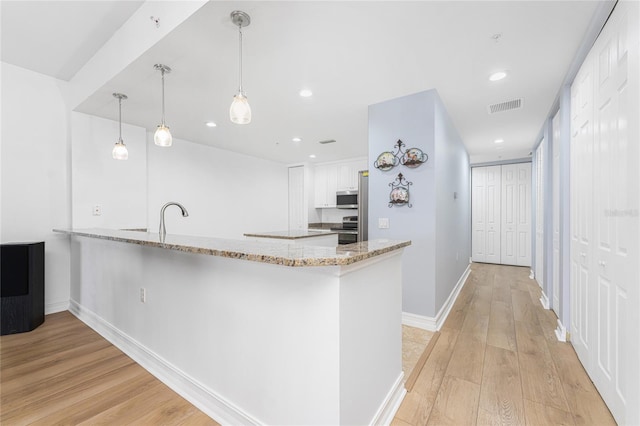 kitchen featuring hanging light fixtures, stainless steel appliances, kitchen peninsula, light hardwood / wood-style floors, and white cabinets