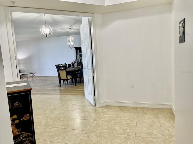 corridor featuring an inviting chandelier and light tile patterned flooring