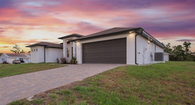 view of front of property with a lawn, central AC, and a garage