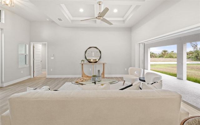 living room featuring a raised ceiling, ceiling fan, light hardwood / wood-style floors, and a high ceiling