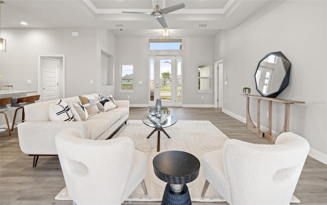 living room featuring a raised ceiling, ceiling fan, a towering ceiling, and wood-type flooring