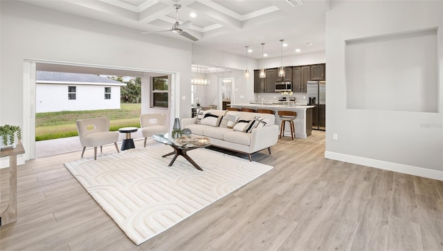 living room featuring a towering ceiling, coffered ceiling, ceiling fan, beam ceiling, and light hardwood / wood-style floors