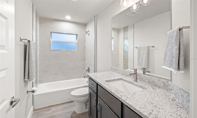 full bathroom featuring hardwood / wood-style floors, vanity, toilet, and tiled shower / bath