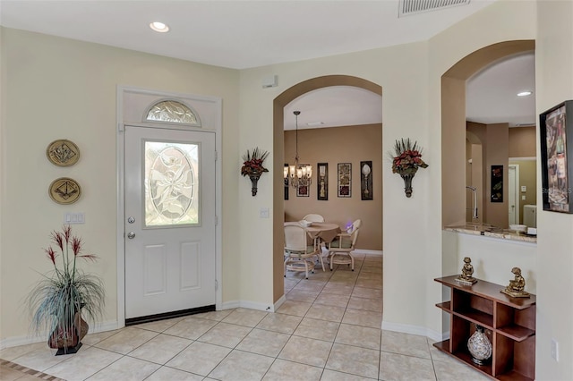 tiled foyer entrance with an inviting chandelier