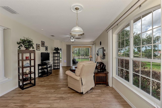 living area featuring ceiling fan and ornate columns