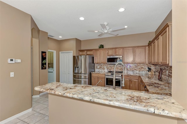 kitchen featuring tasteful backsplash, stainless steel appliances, kitchen peninsula, and light tile patterned floors