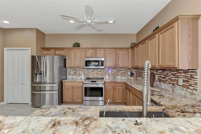 kitchen with light tile patterned flooring, sink, light stone counters, stainless steel appliances, and decorative backsplash