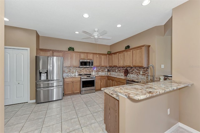 kitchen featuring light tile patterned floors, appliances with stainless steel finishes, light stone counters, decorative backsplash, and kitchen peninsula