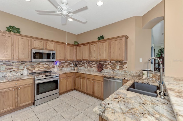 kitchen featuring light tile patterned flooring, appliances with stainless steel finishes, sink, and light stone counters